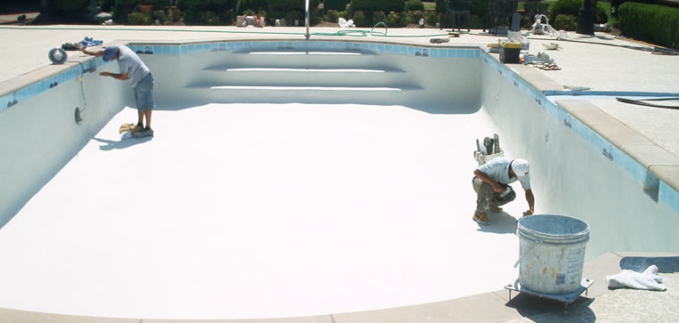 Workers applying plaster to a swimming pool during resurfacing, showcasing a clean, white surface and tools for pool maintenance.