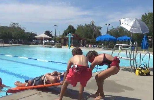 Lifeguards performing a rescue drill at a swimming pool, demonstrating safety protocols and emergency response training for aquatic facilities.