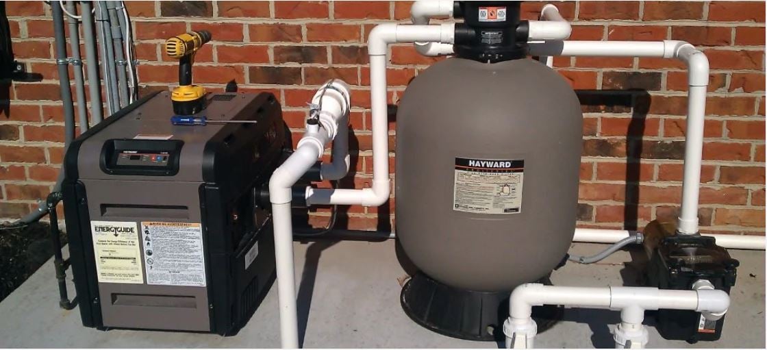 Pool equipment setup featuring a Hayward filter, pump, and energy-efficient heater, illustrating essential components for aquatic facility maintenance and performance.